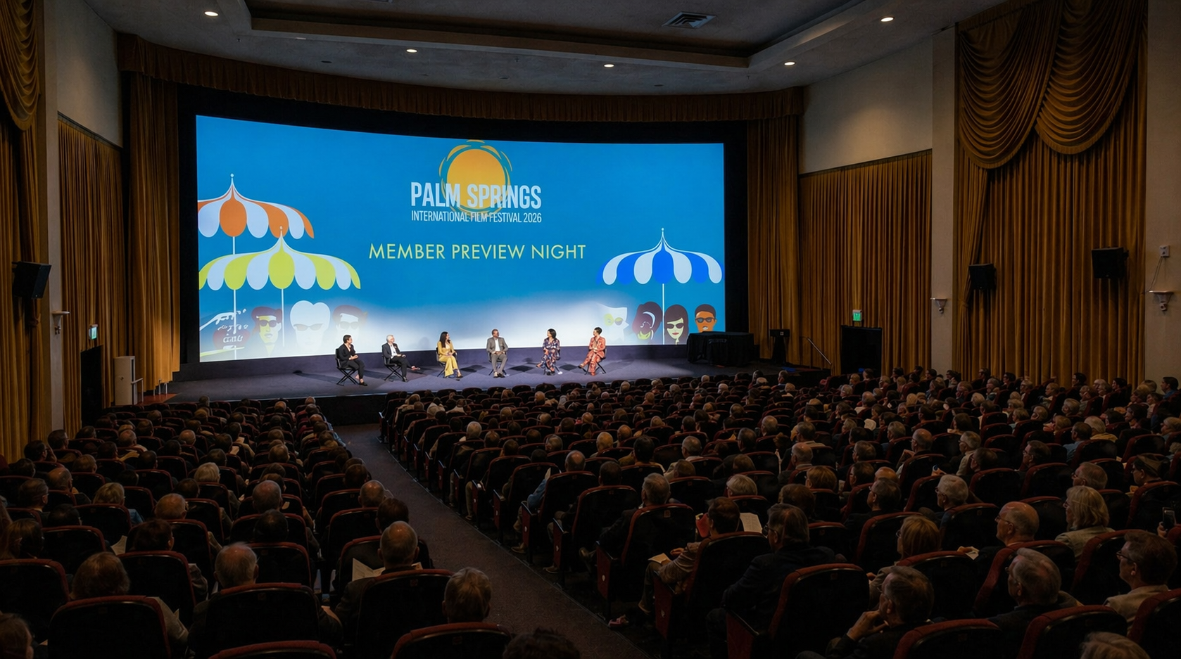 Conference audience facing a stage with five panelists and a large blue screen backdrop in an auditorium