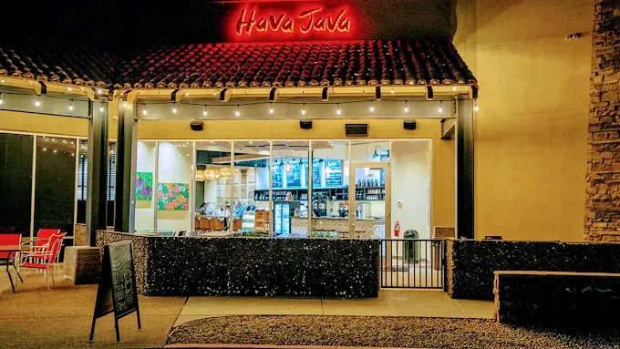 Have Java coffee shop exterior at night, lit by red neon sign. Glass windows, outdoor seating visible.
