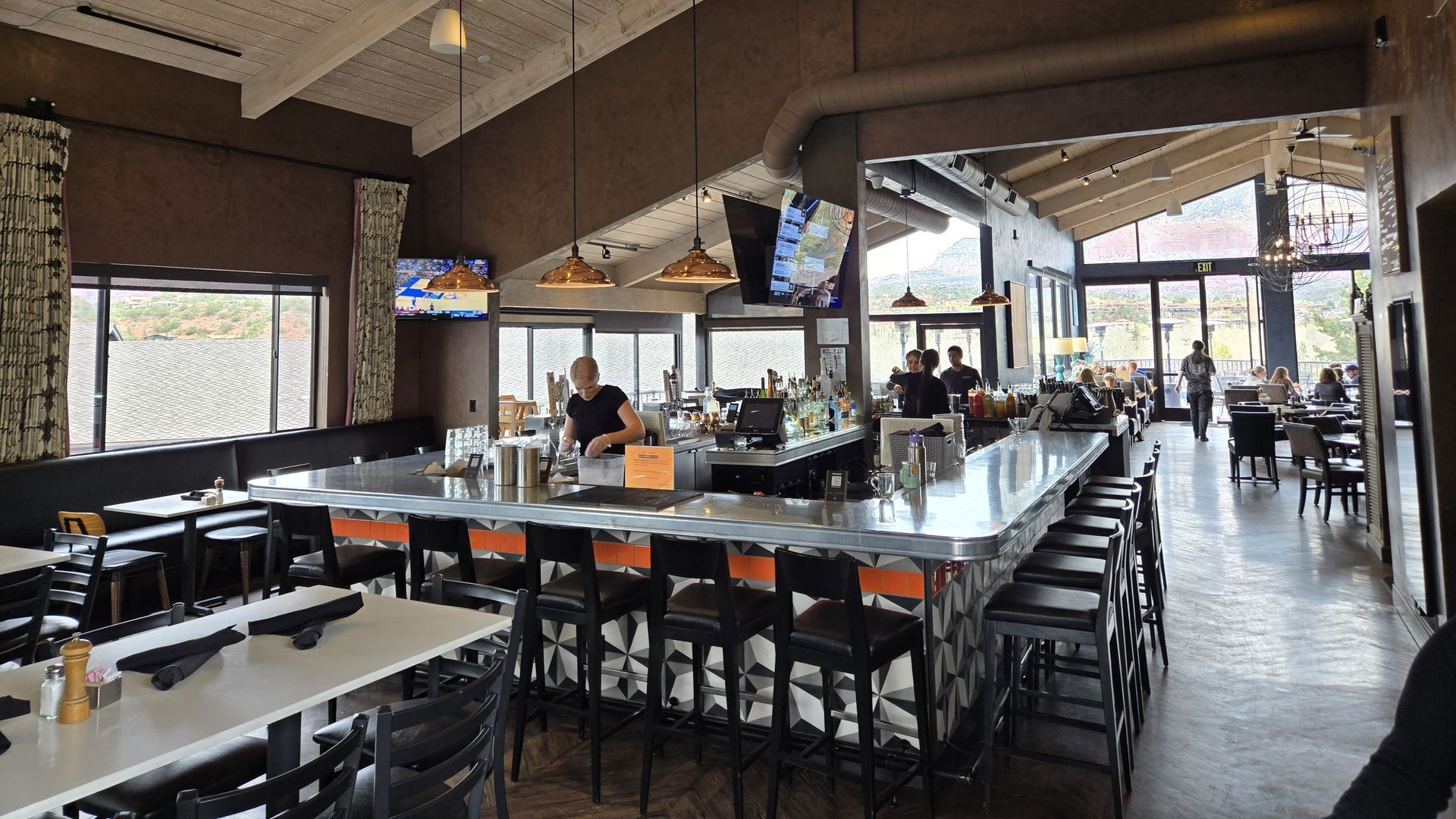 Interior view of a modern restaurant with a bar and dining area. People are present; neutral lighting.