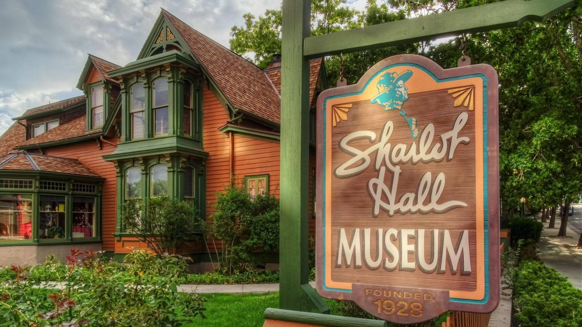 Shiloh Hall Museum with a sign in front, featuring a brick building with green trim and a clay tile roof.