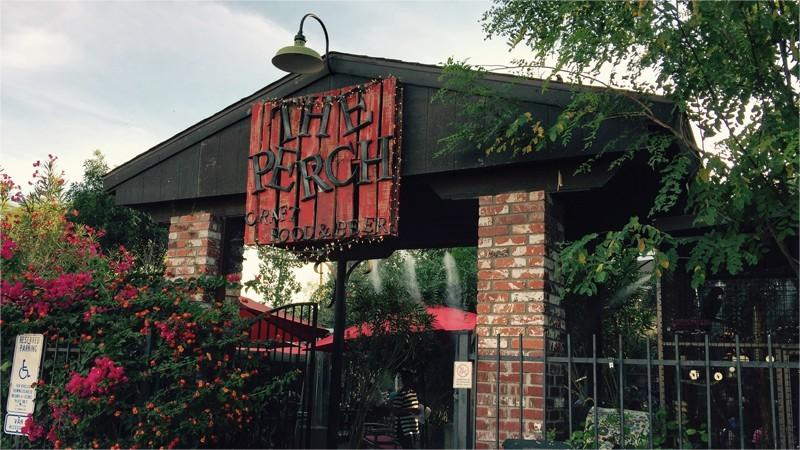 Entrance to the White Perch restaurant, featuring a brick archway, sign, and gate with landscaping.