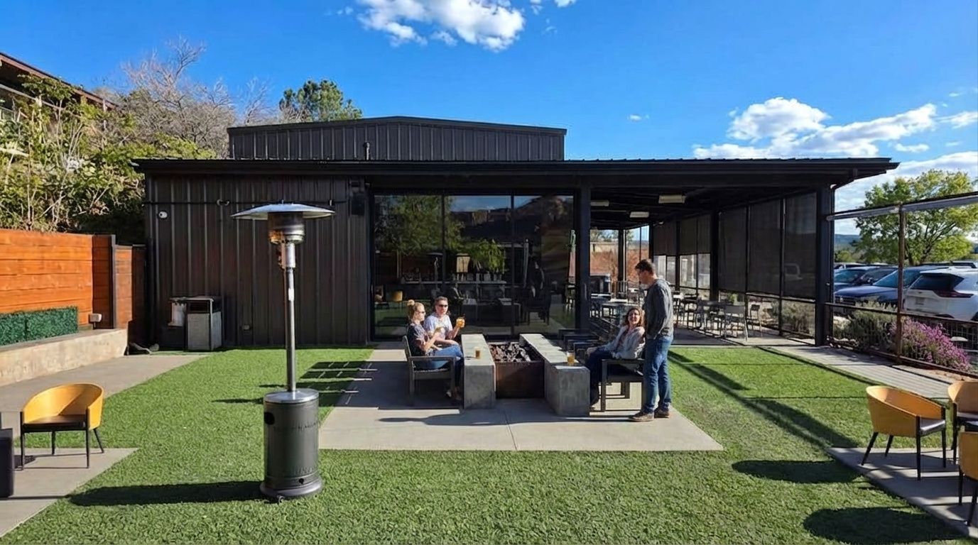 An outdoor restaurant patio with a fire pit, seating, and a propane heater on a sunny day.