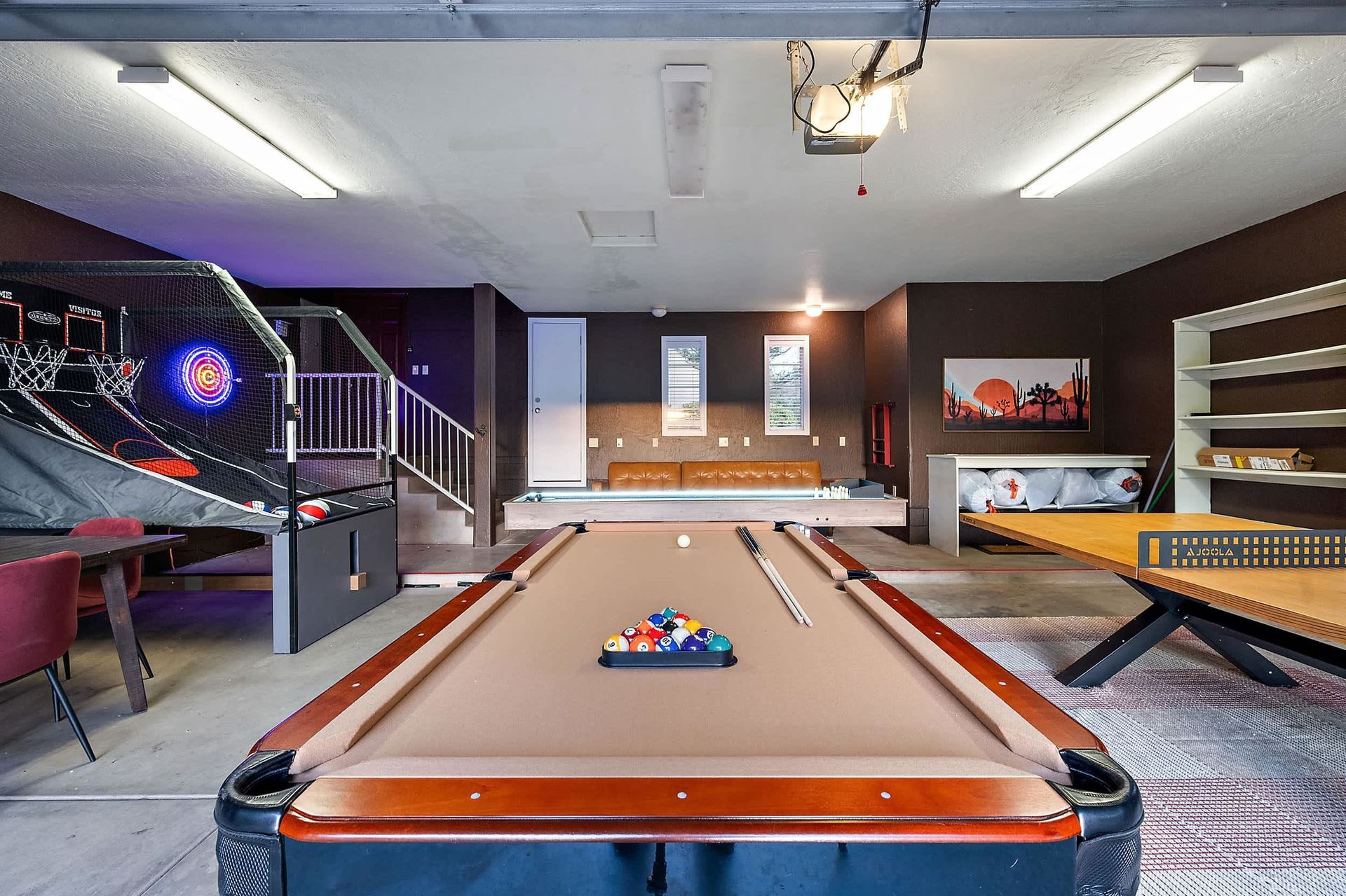 Game room with pool table, dartboard, and arcade machine in a modern basement.