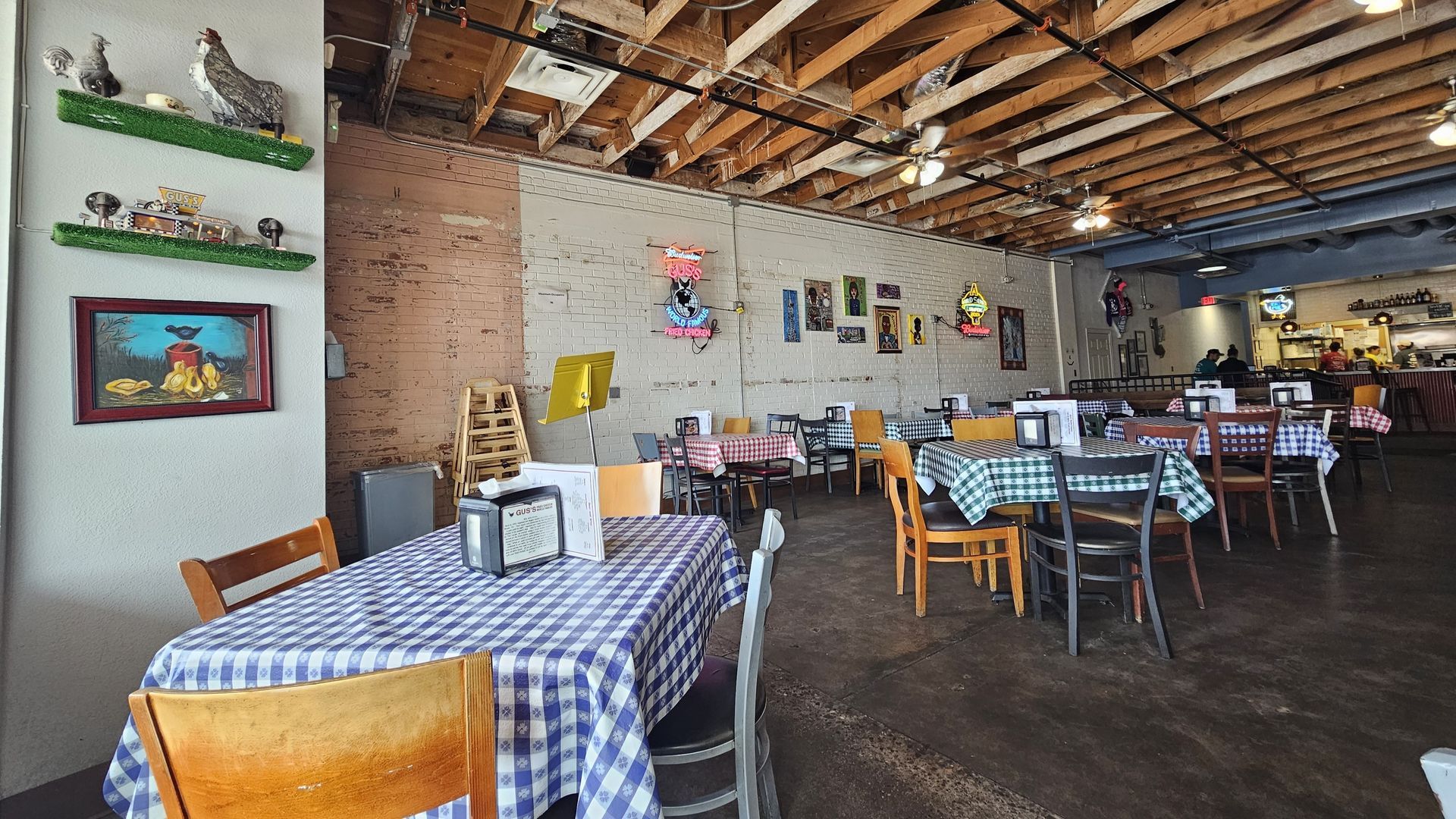 Restaurant interior with checkered tablecloths, wooden chairs, and decorations on the wall.