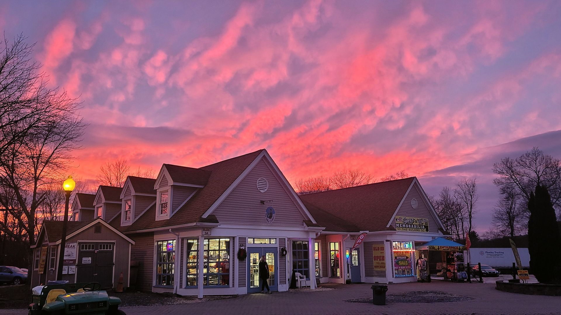 A commercial building with a brightly lit storefront under a vibrant pink and purple sunset sky.
