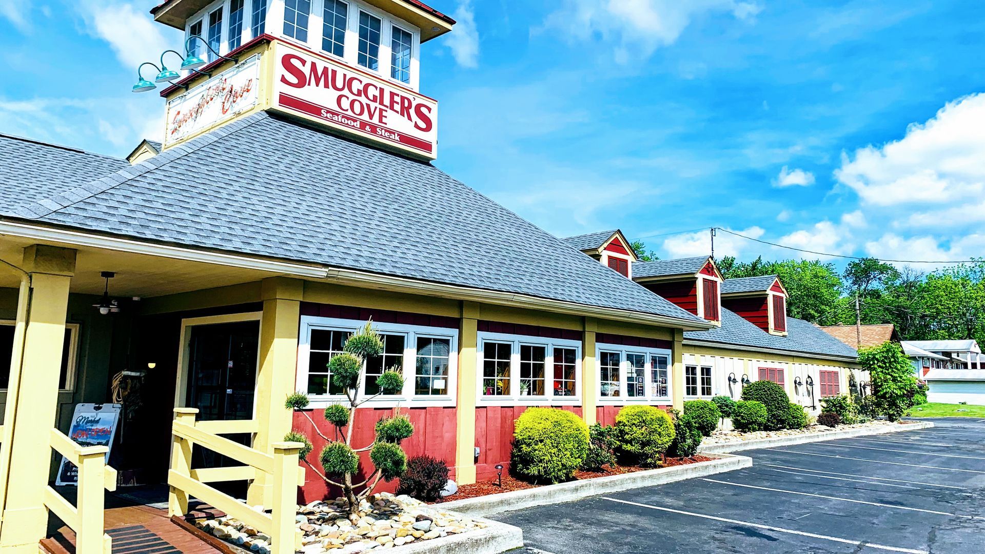 Smugglers Cove restaurant exterior with red and yellow accents under a blue sky.