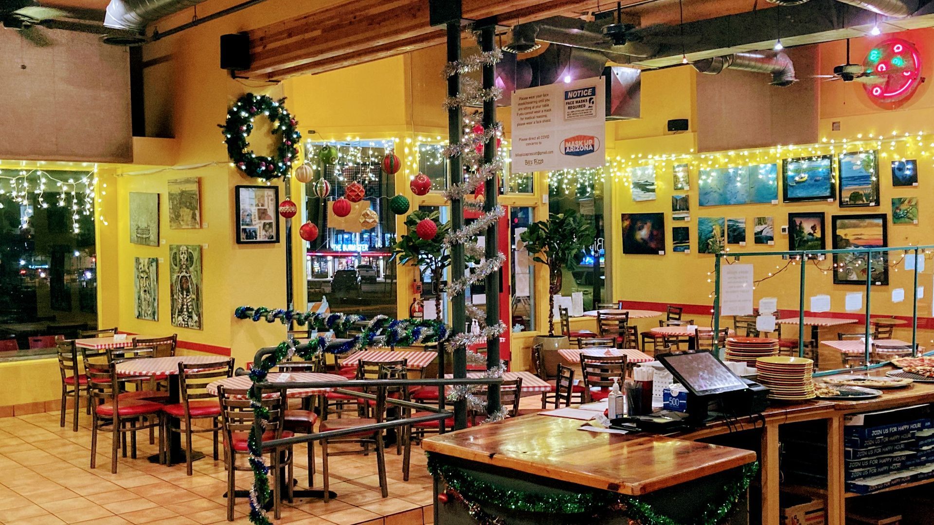 Restaurant interior decorated for Christmas, yellow walls, tables, and a bar.