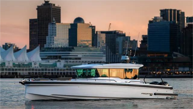 White motorboat on water with a city skyline in the background, lit by a sunset.