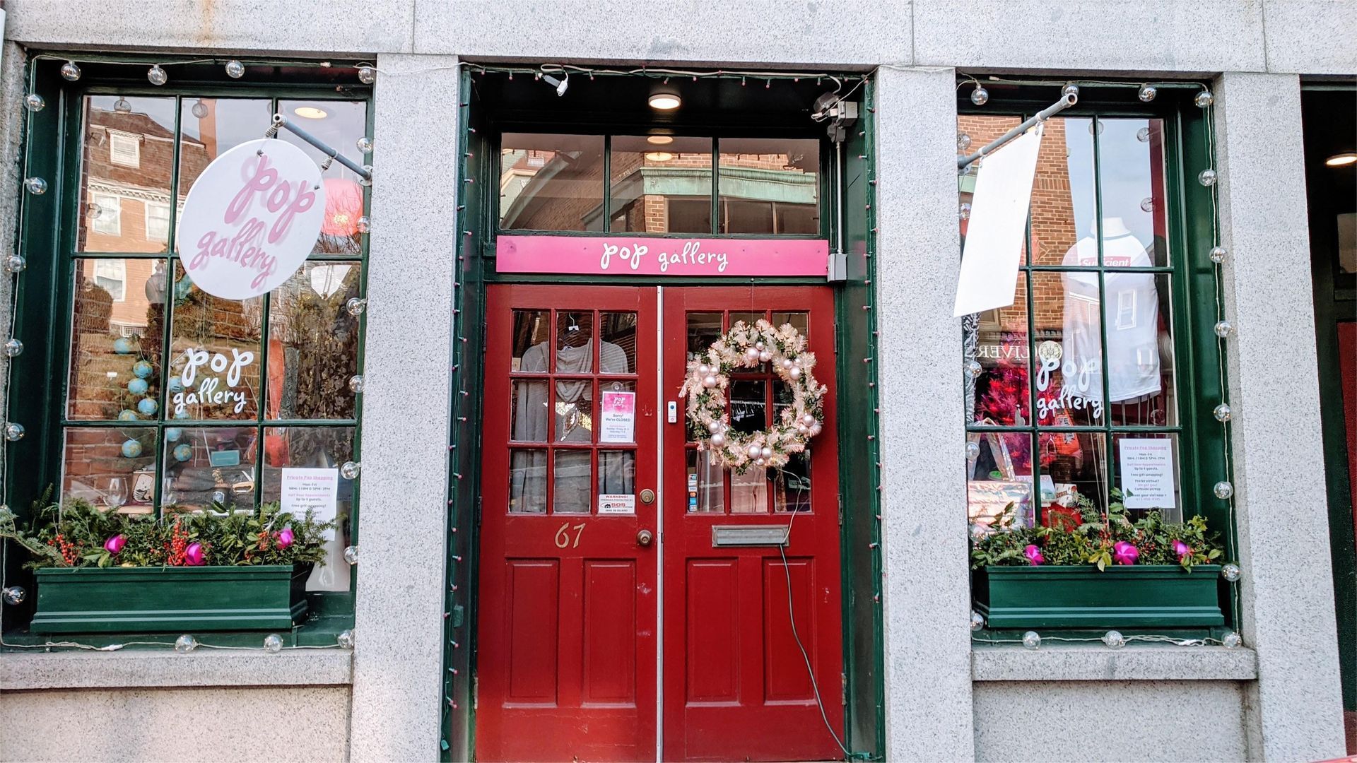 Storefront with red doors, wreath, and windows with seasonal decorations. 