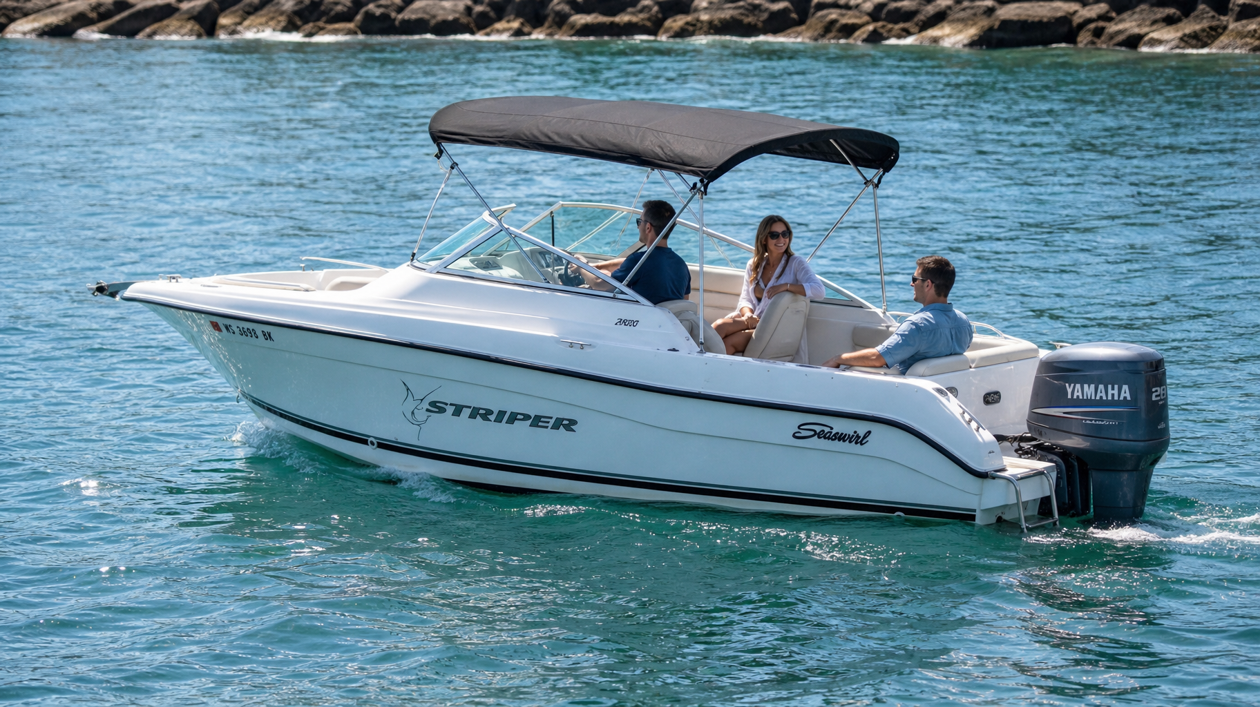 White motorboat with people cruising on turquoise water near a rocky shoreline