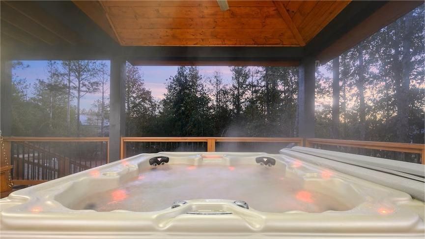 Hot tub on a deck, steam rising, forest background at dusk.