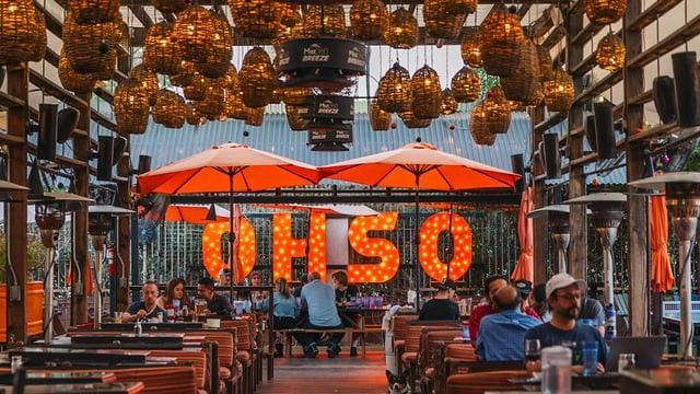 Outdoor restaurant with orange umbrellas and illuminated 