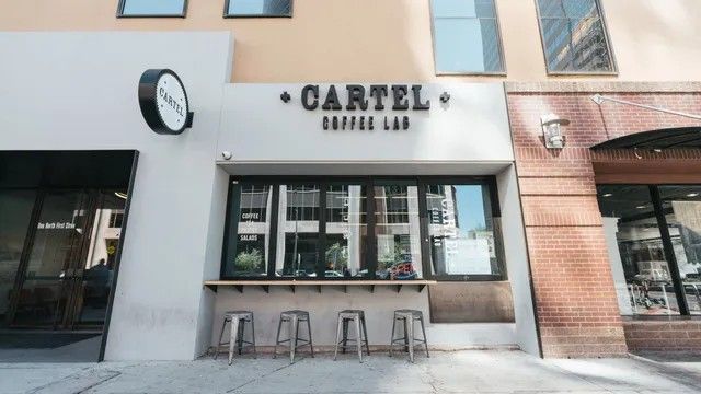 Cartel Coffee Lab storefront with black sign, window, and stools.