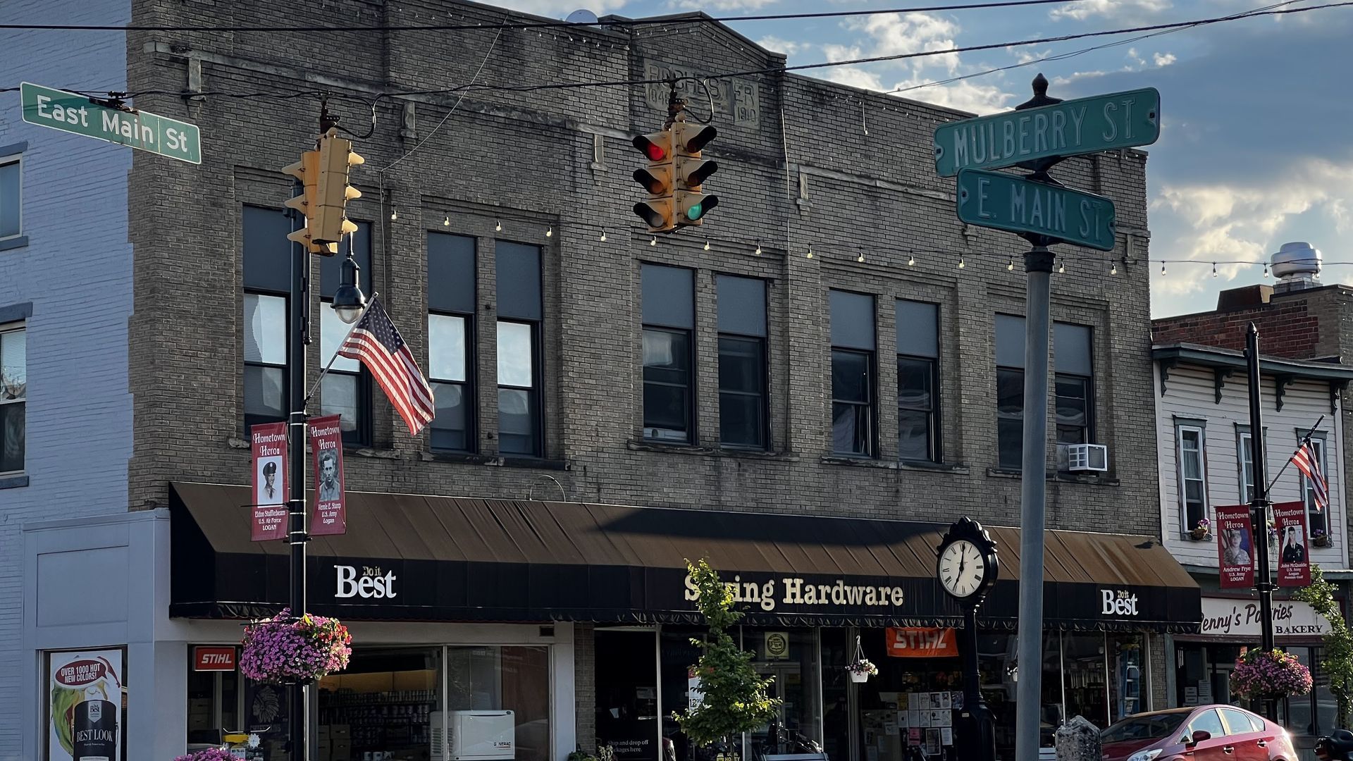 Storefronts on a street corner, with brick buildings, traffic lights, and street signs.