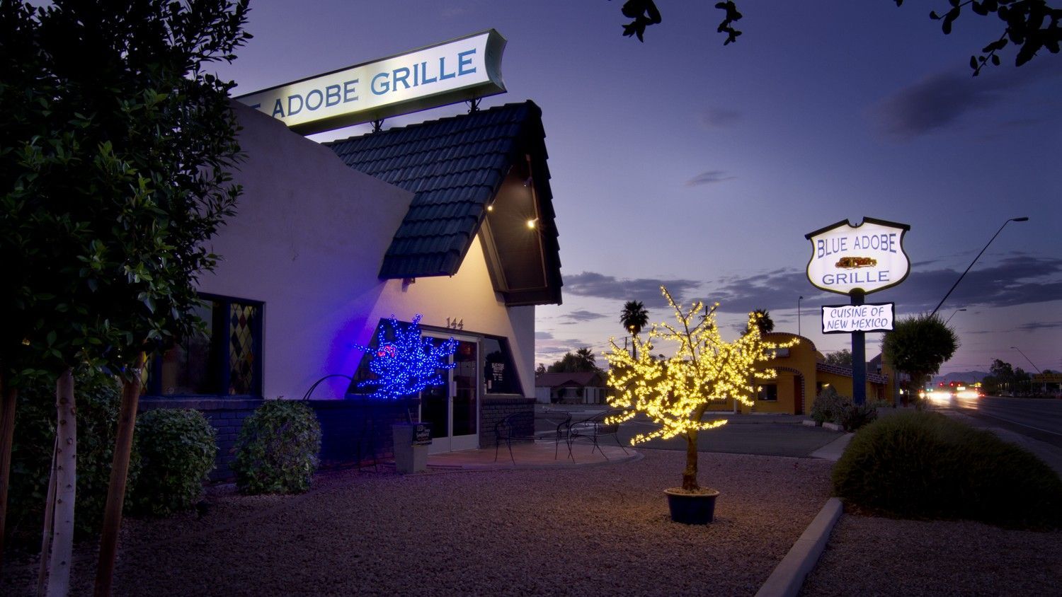 Adobe Grille restaurant at dusk with illuminated sign and lights.