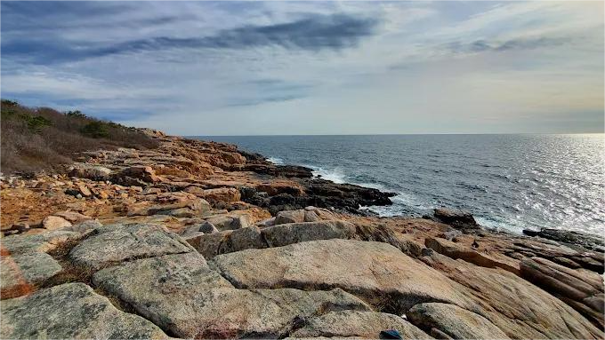 Rocky coastline with the ocean under a blue sky.