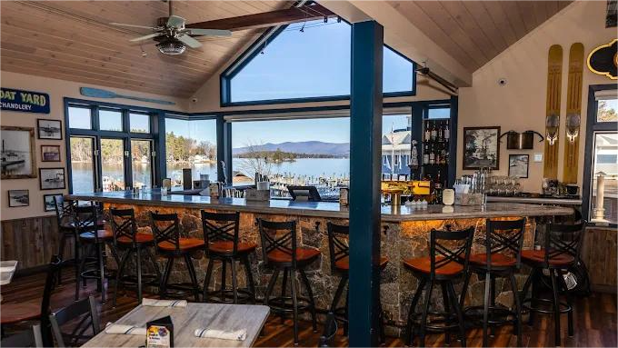 Bar with lake view, stone front, orange bar stools, skis on wall.