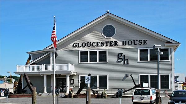 Gloucester House restaurant, two-story gray building, American flag, water views.