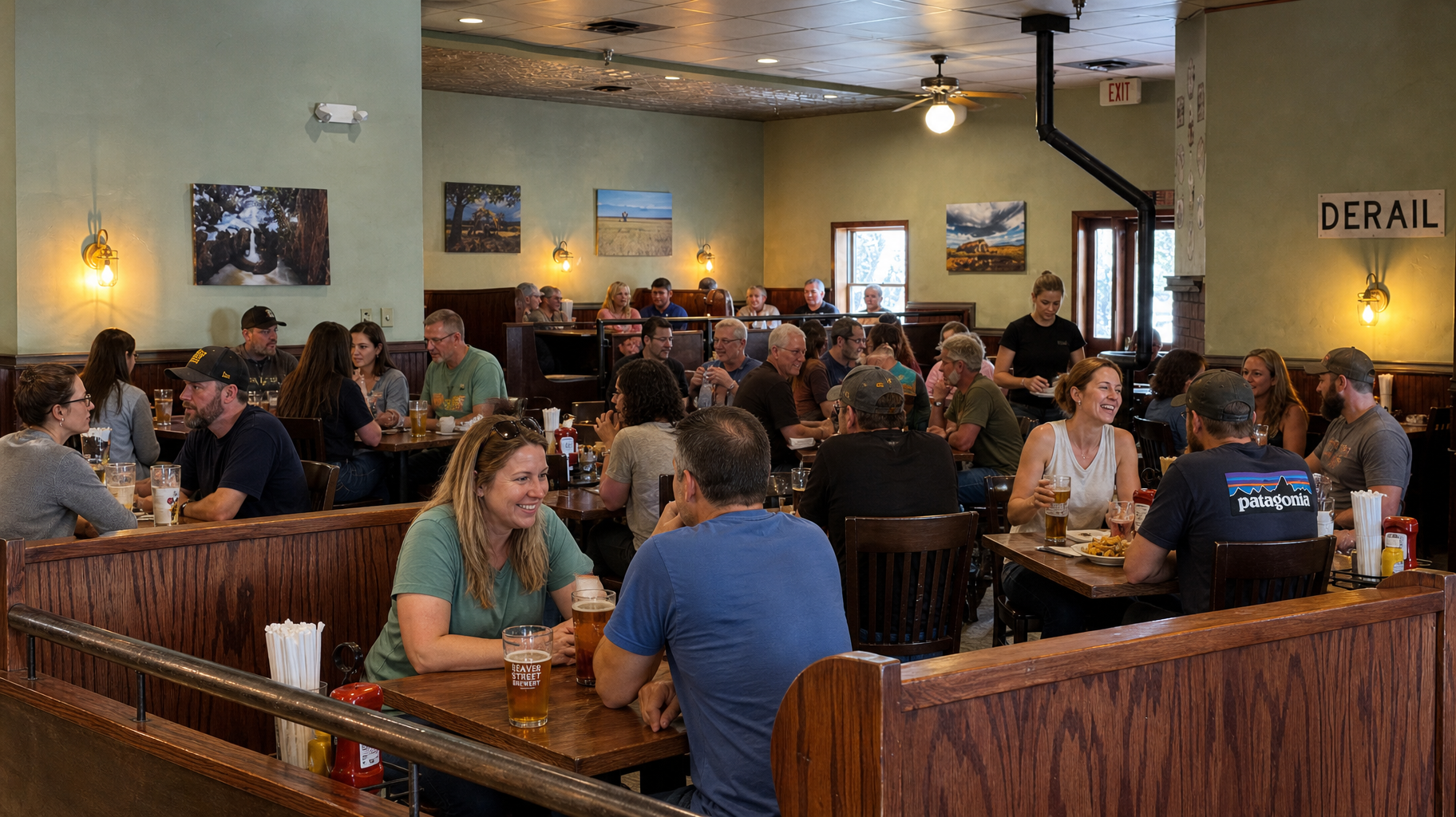 Crowded restaurant dining room with people eating at wooden booths and tables under warm lighting