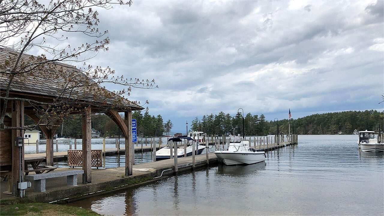 Dock with boats on water under a cloudy sky near a wooden building.