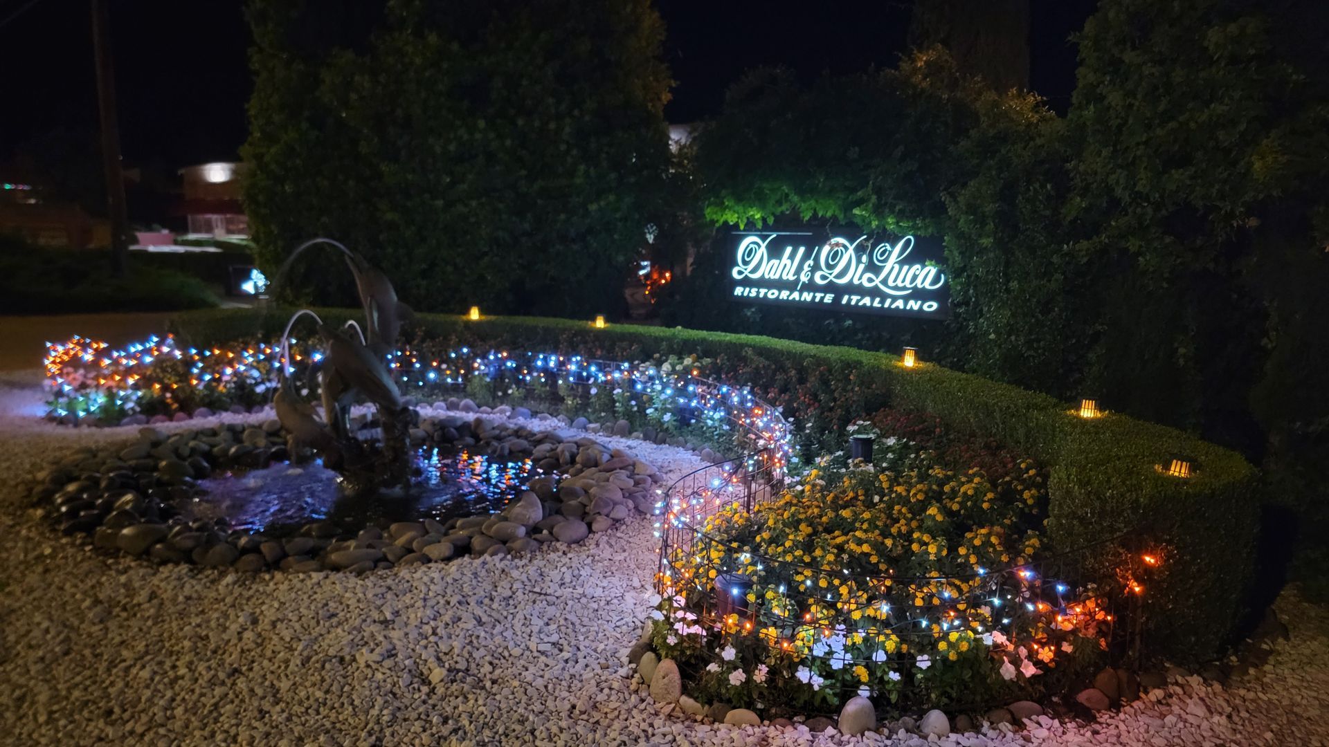 Sign for Patti’s 1880's Settlement at night, illuminated with colorful lights and a small fountain.