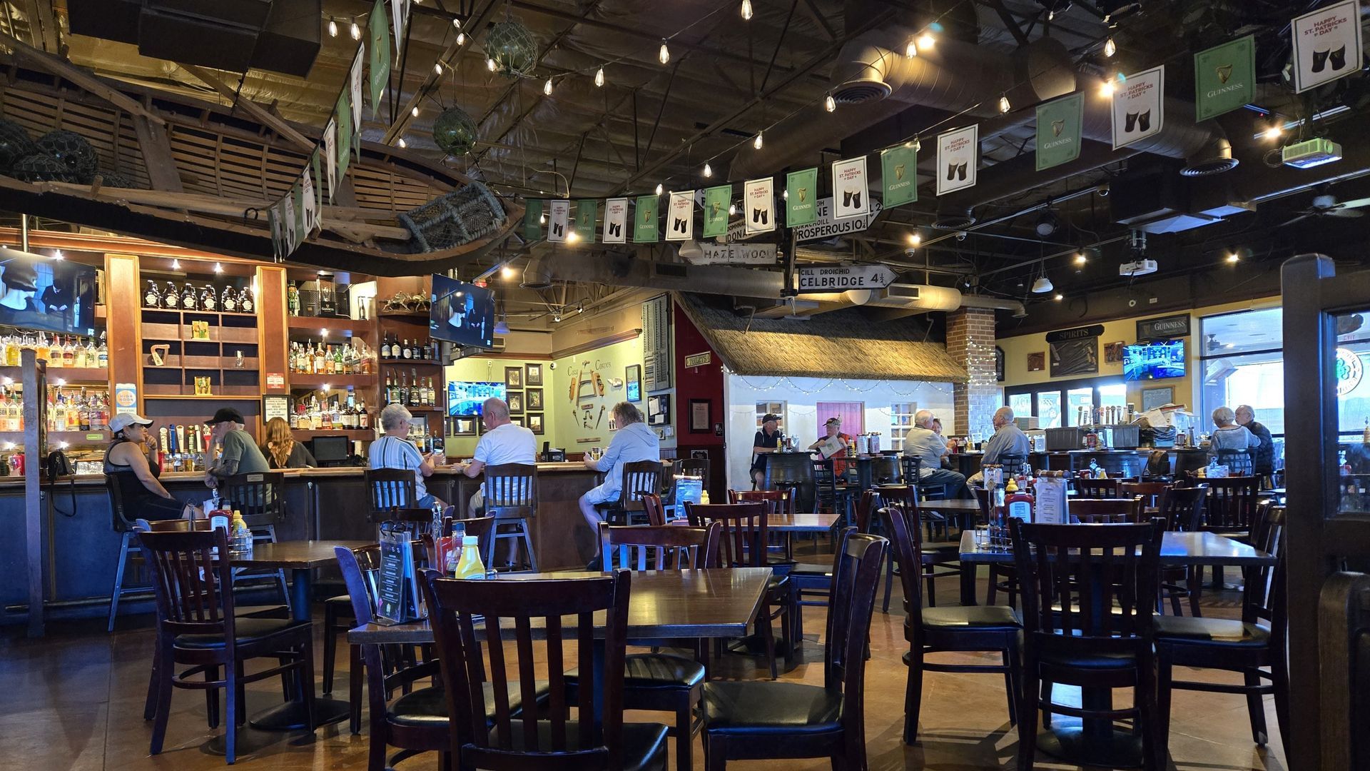 Interior of a pub with bar, tables, chairs, people seated, and decorations.