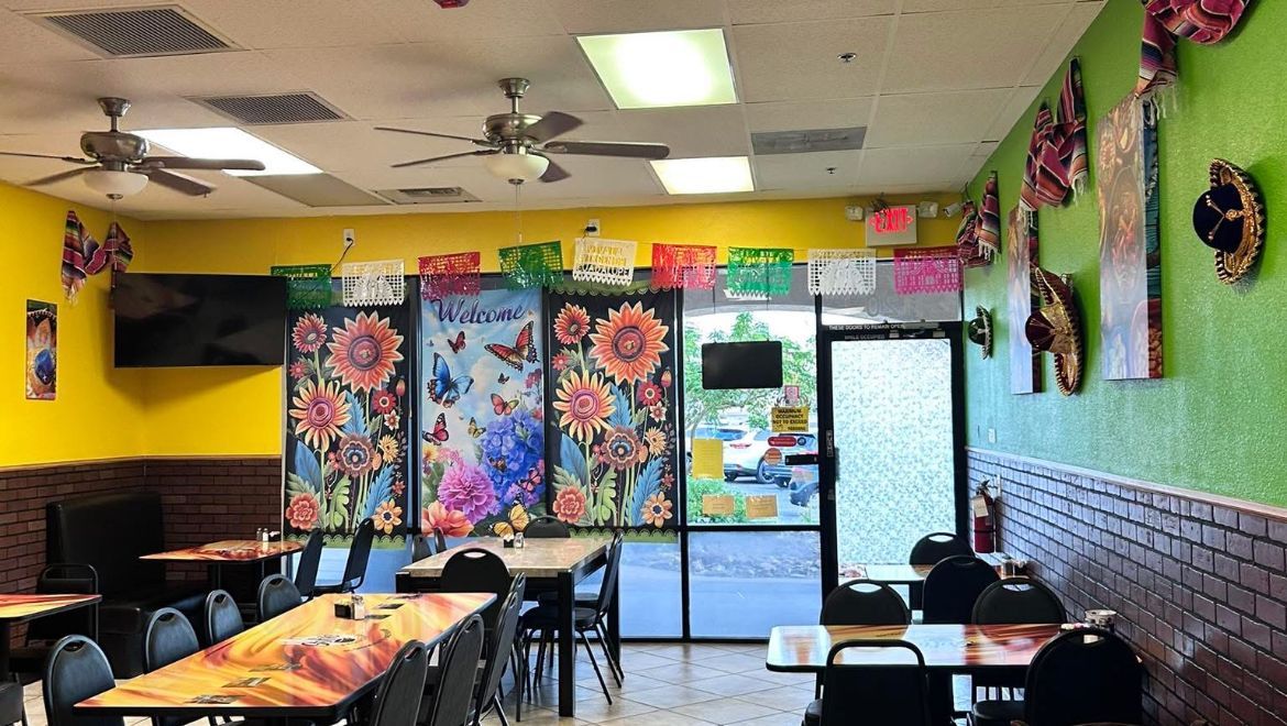 Interior of a Mexican restaurant with tables, colorful decorations, and a door to the outside.