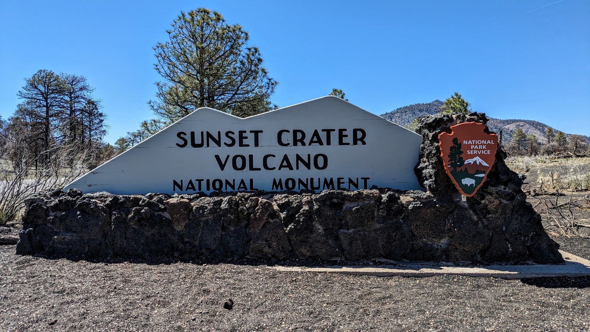 Sunset Crater Volcano National Monument sign with the National Park Service logo.