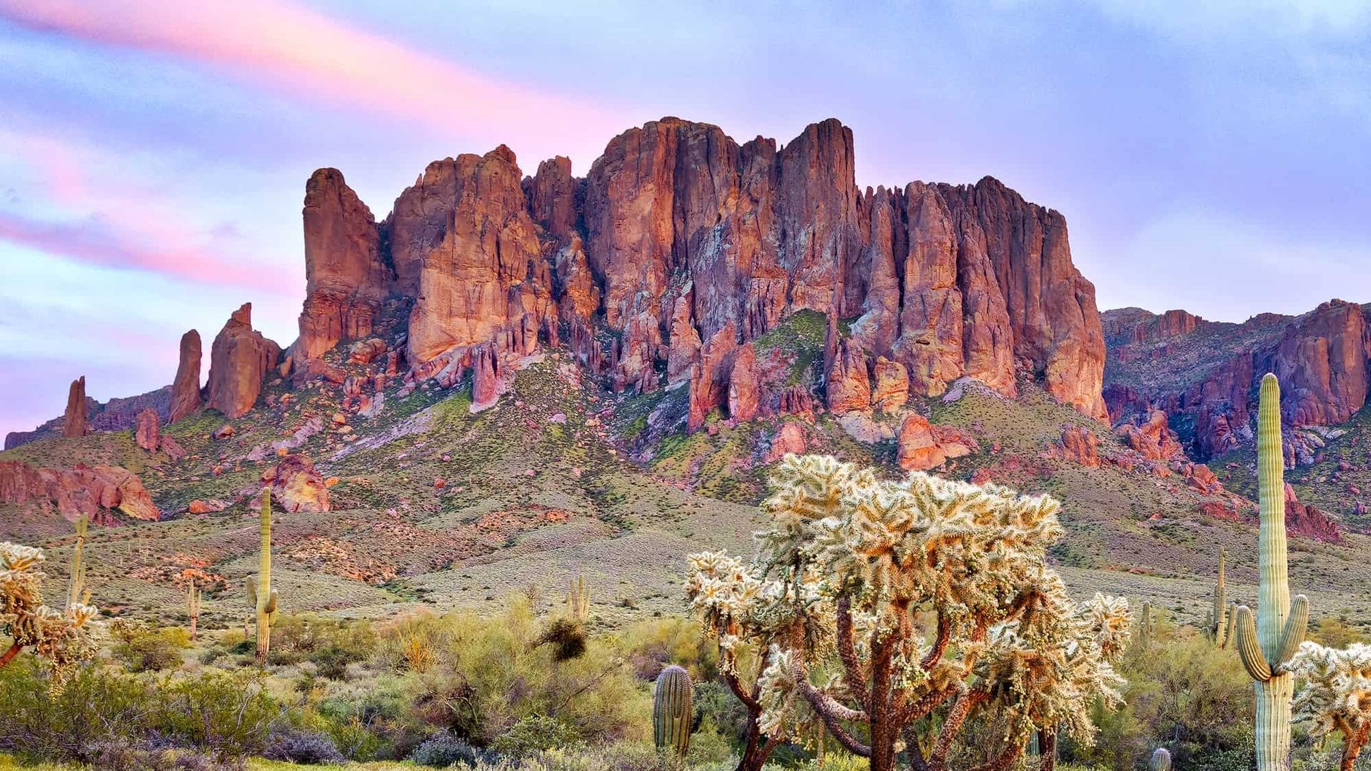 Desert landscape with rock formations bathed in warm light under a pastel sky.