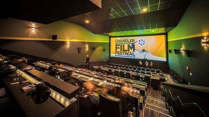 Interior of a movie theater with a screen displaying a film festival logo. Rows of seats are visible.