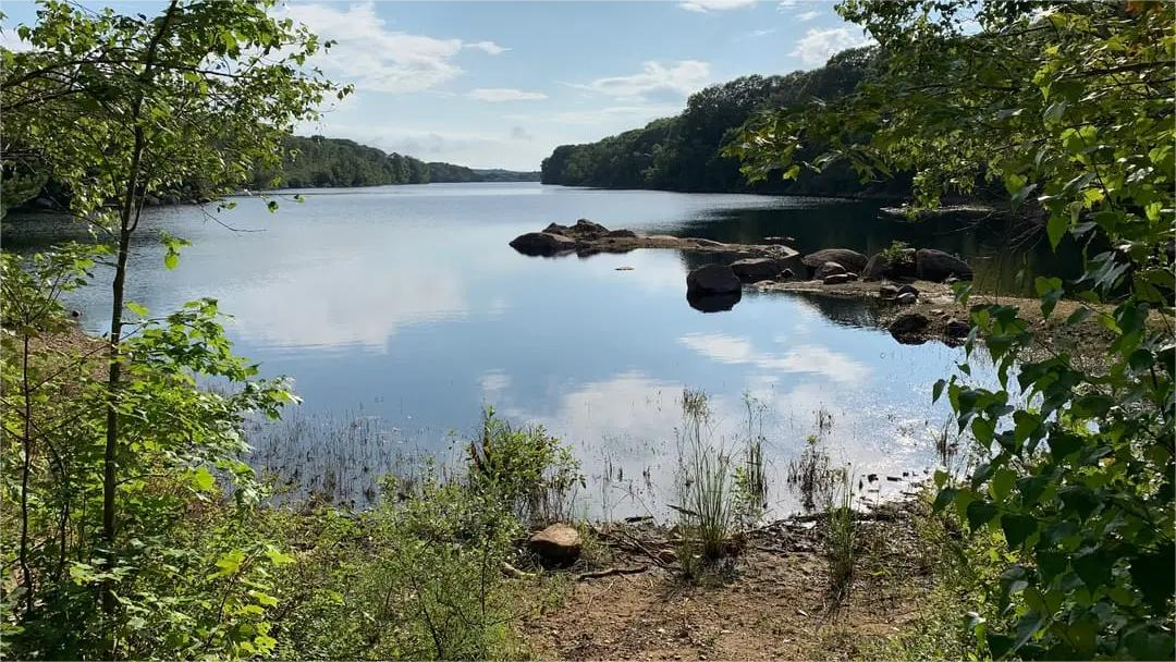 Lake with trees and blue sky reflected in the water.