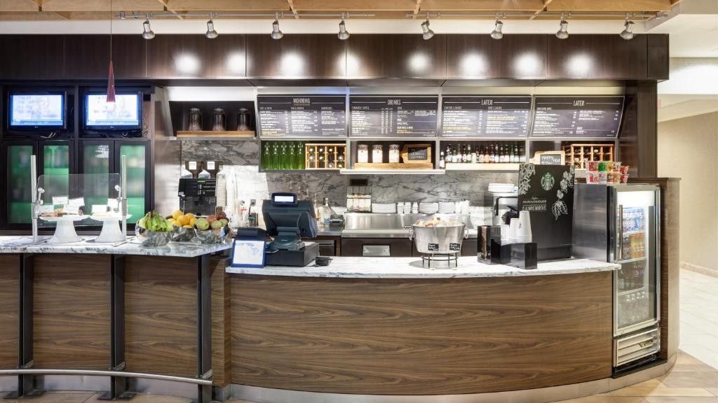 Coffee shop counter with menu boards, drinks, and food displays.