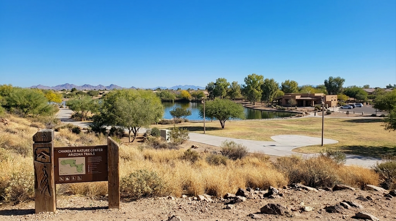 Desert park with a small pond, trees, dry grass, and a wooden sign in the foreground under a clear blue sky.