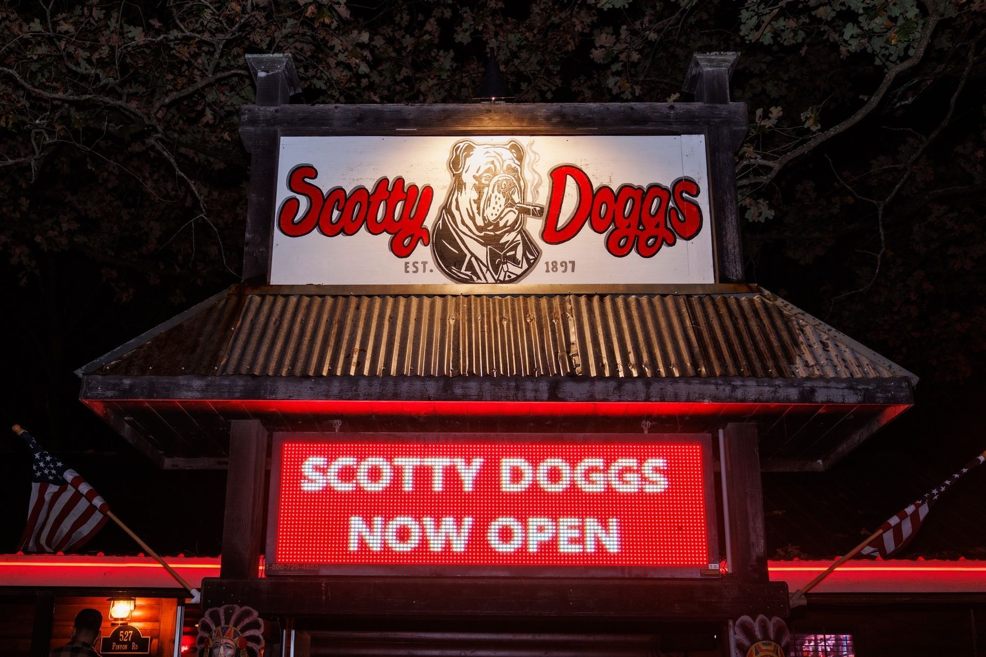 Sign for Scotty Doggs restaurant, lit up at night. Red and white lettering with a dog illustration.