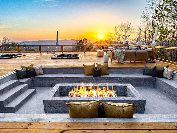 Modern lakeside patio with a fire pit, built-in seating, and sunset views over the water