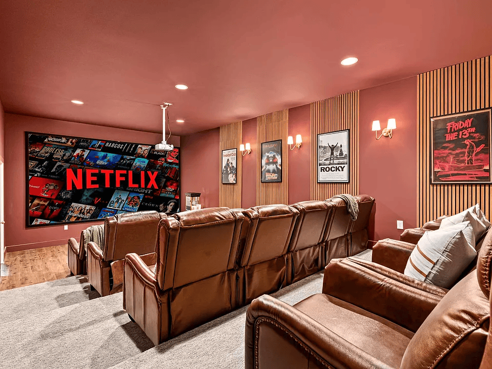 Home theater with brown recliners, red walls, Netflix screen, and movie posters