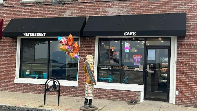 Cafe storefront with black awnings, red brick exterior, and decorative statue and balloons.