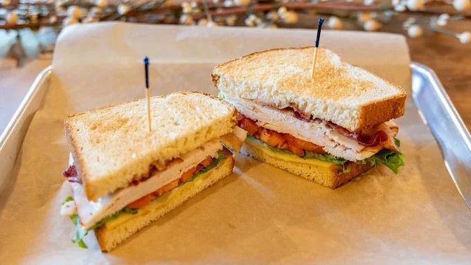 Two club sandwiches on parchment paper.
