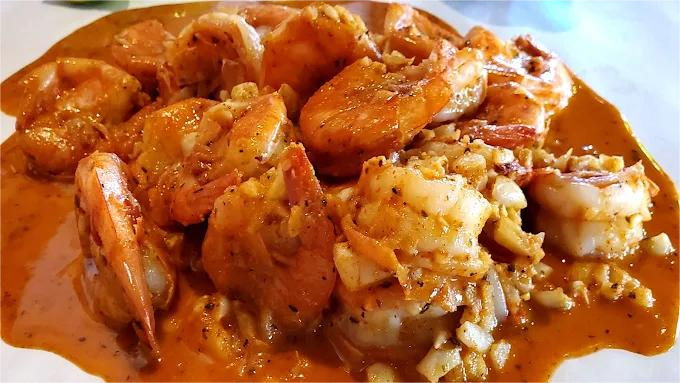 Large shrimp in a creamy orange sauce, served on a bed of rice.