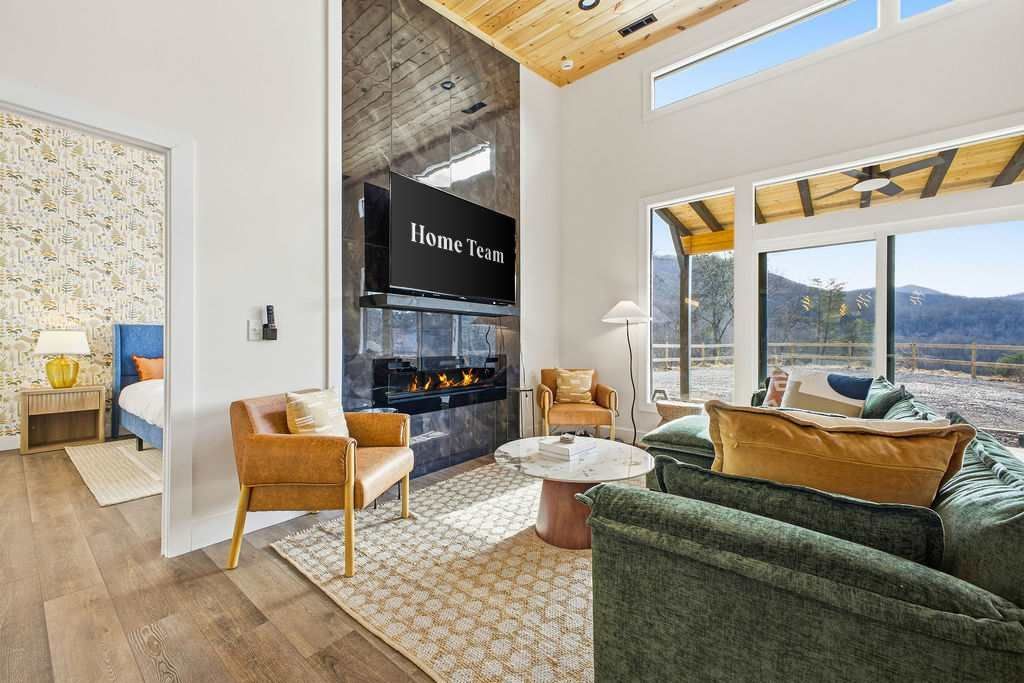 Modern open living room with green sofa, fireplace, wood ceiling, and large windows overlooking the outdoors