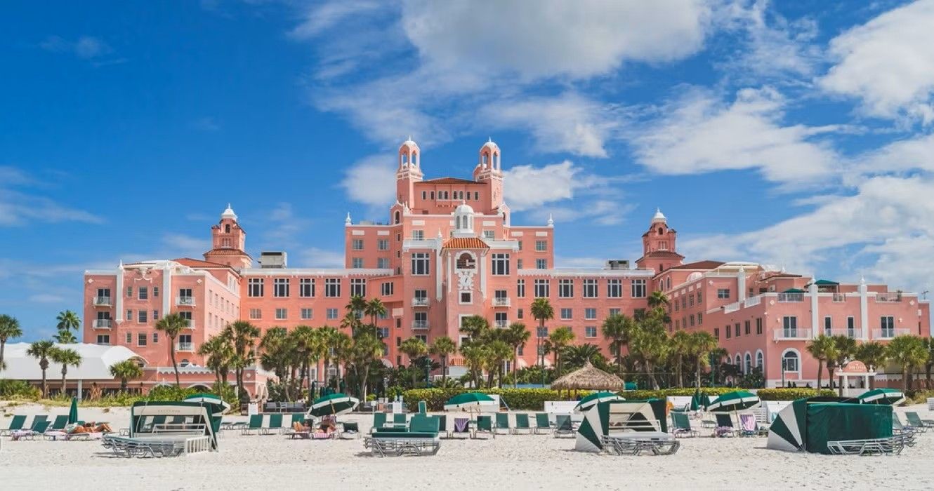 Pink hotel, The Don CeSar, on white sand beach under blue sky.