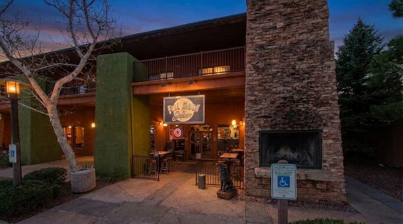 Exterior of the rustic Wild River Grille restaurant at dusk, featuring a stone fireplace and patio seating.