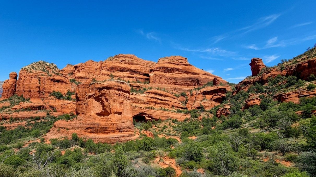 Red sandstone cliffs above green desert shrubs under a clear blue sky