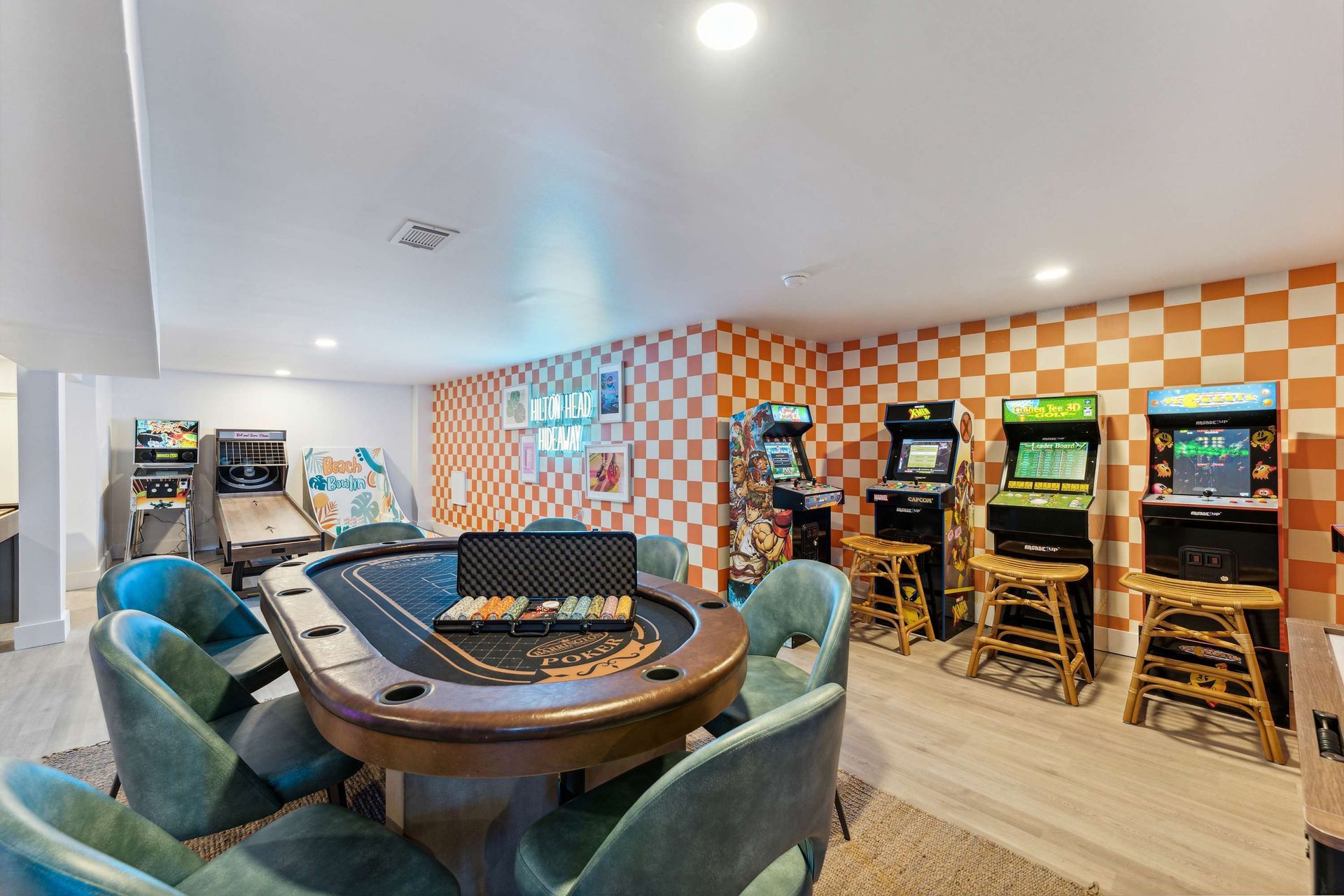 Game room with poker table, green chairs, and arcade machines in a bright finished basement