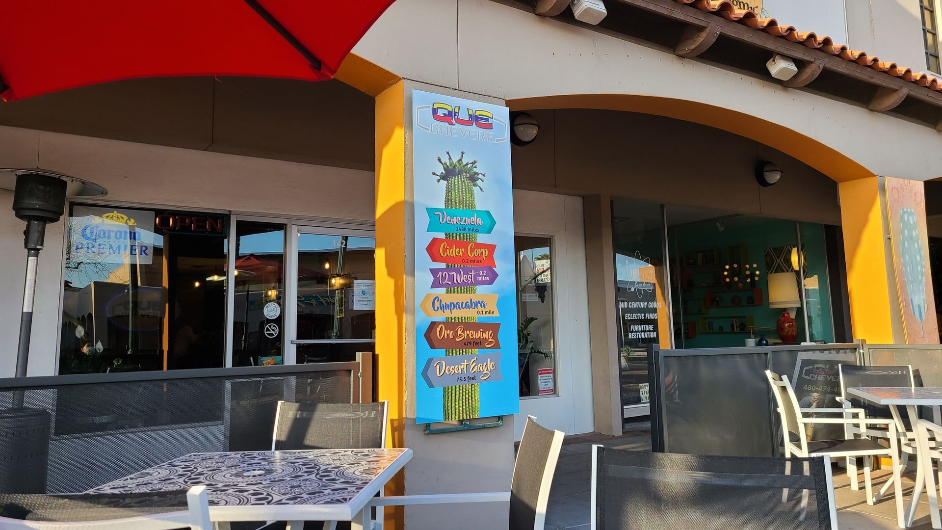 Restaurant exterior with outdoor seating and a hanging sign with directional arrows.