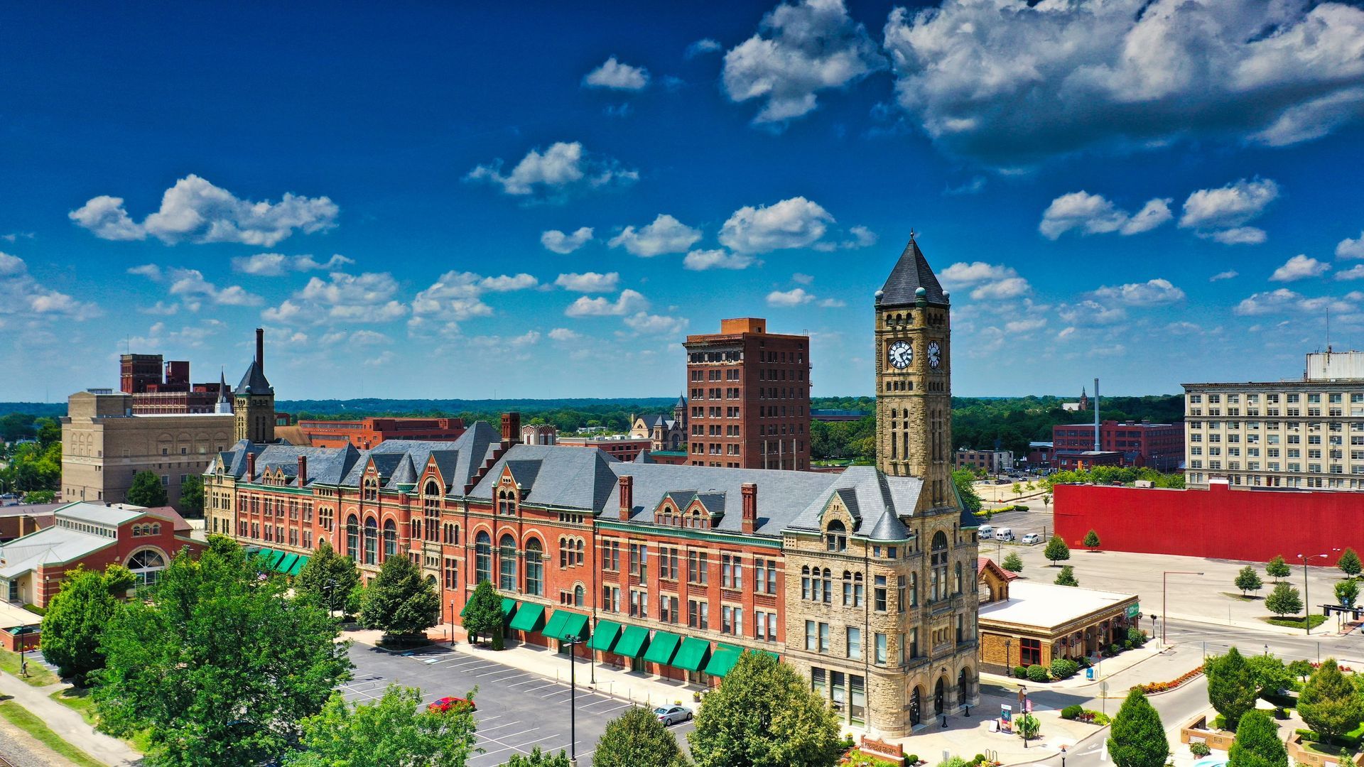 Historic building with clock tower in downtown area under blue sky and clouds.