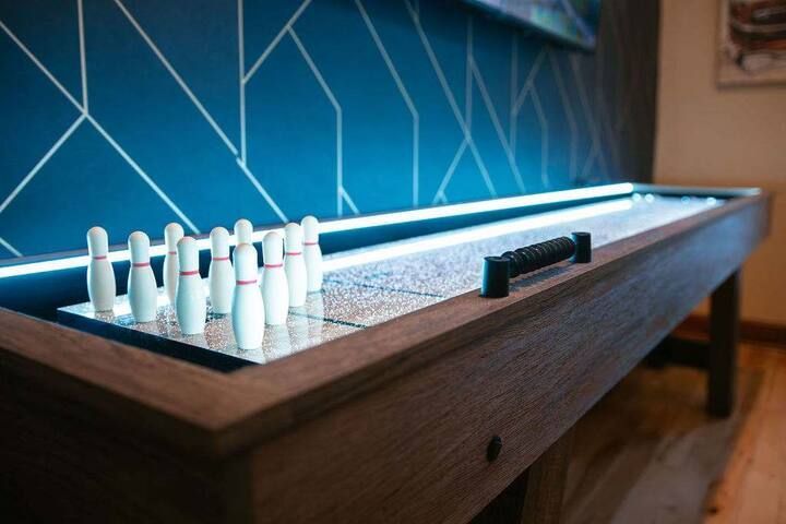 Mini shuffleboard table with white and black pucks on a wooden surface near a blue wall