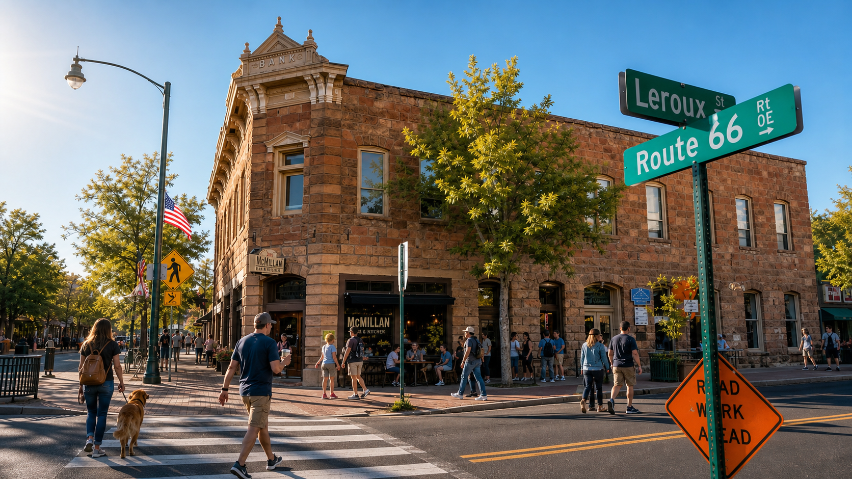 Corner building at a sunny street intersection with a green “Route 66” sign and pedestrians walking nearby