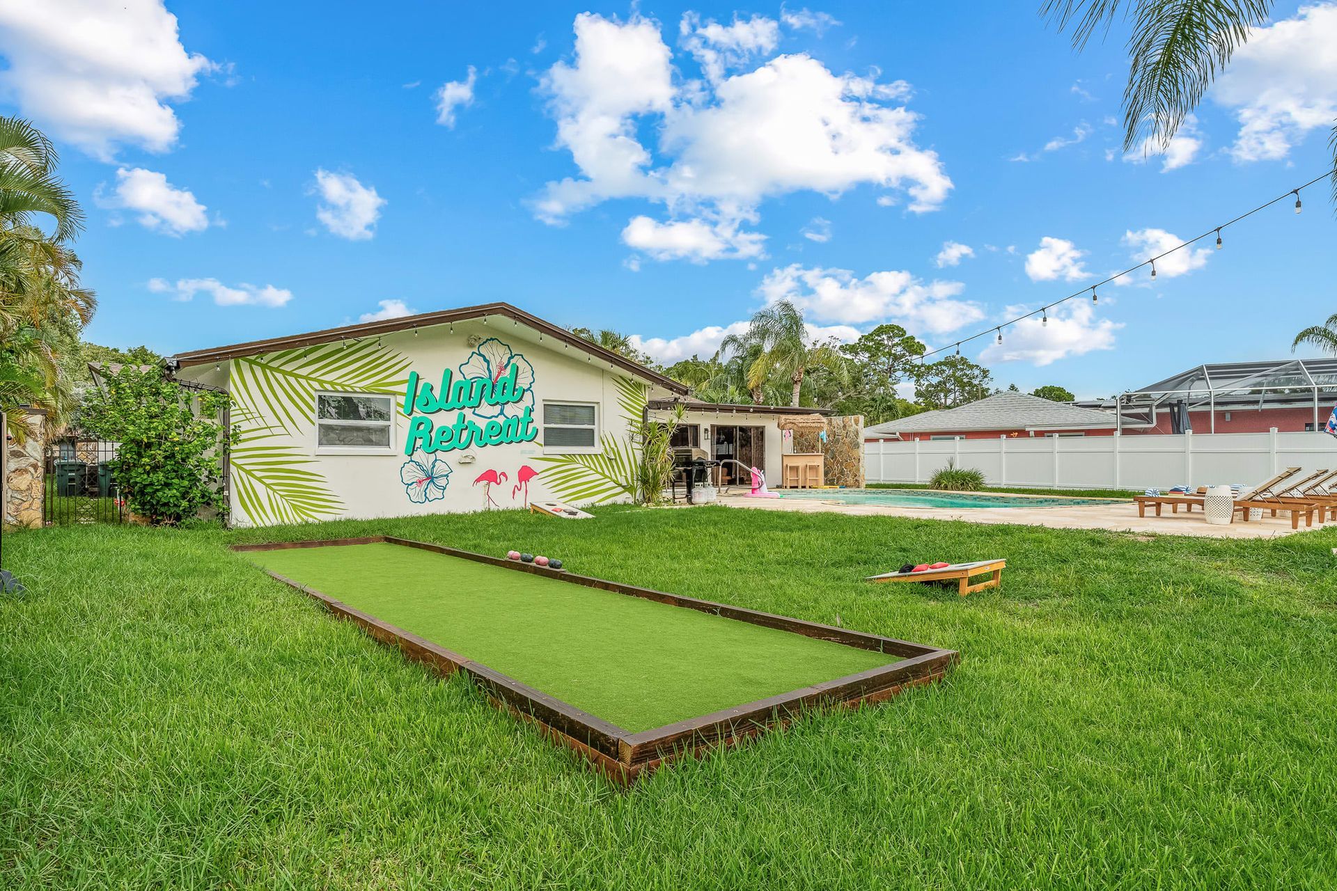 Green lawn with a low white building and sign under a bright blue sky with clouds