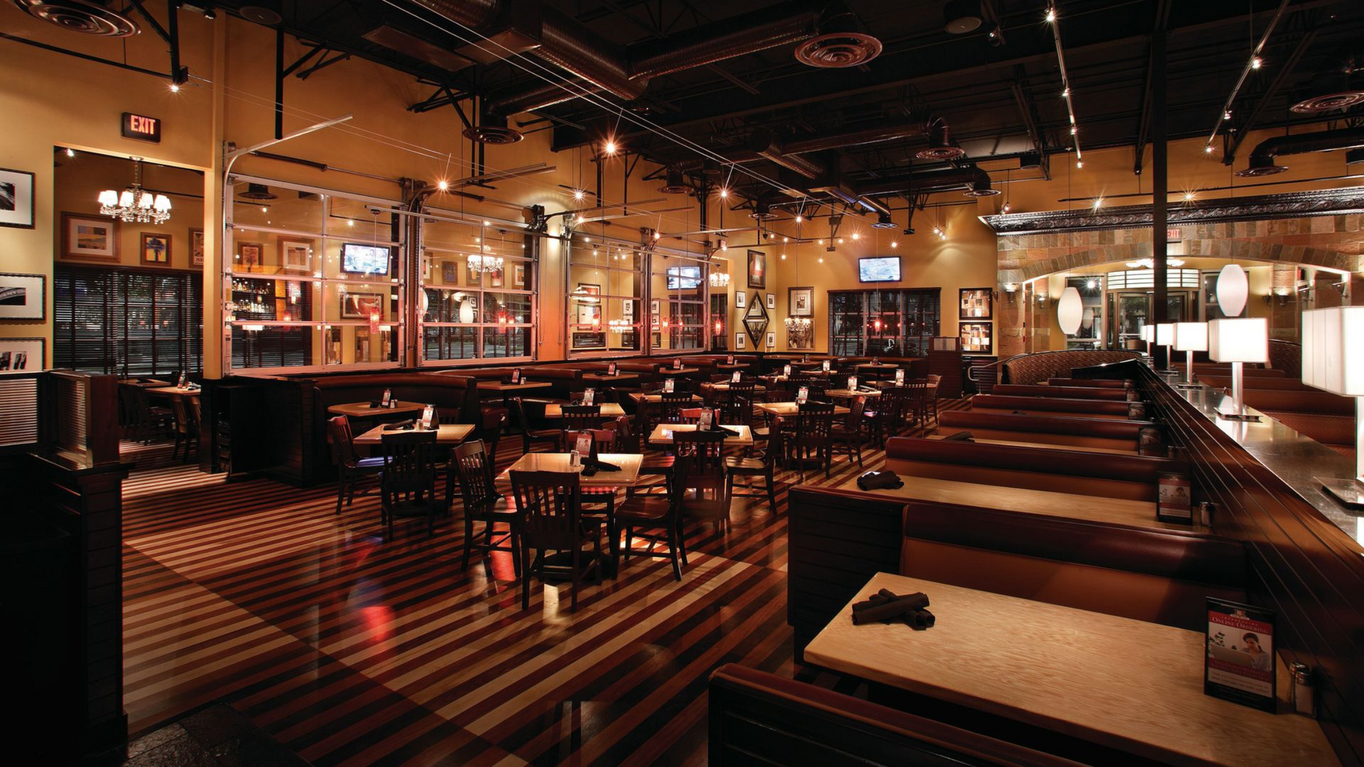 Interior of a dimly lit restaurant with tables, booths, and decorations on the walls.